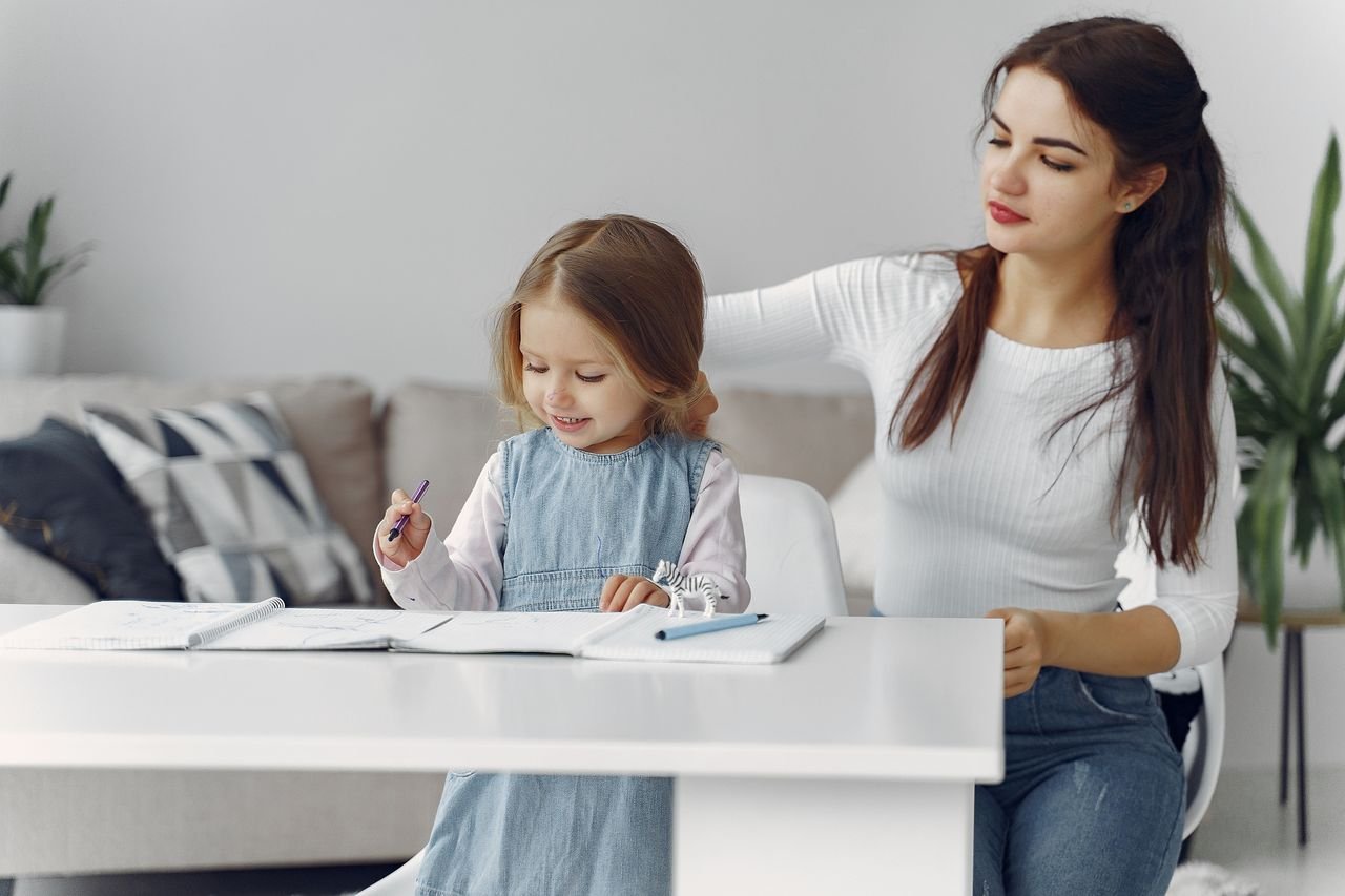 A loving mother helps her daughter with homework at home, fostering a nurturing learning environment.